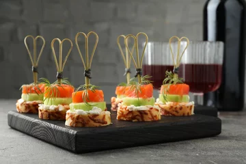 Tuinposter Tasty canapes with salmon, cucumber, bread and cream cheese served on grey table, closeup © New Africa