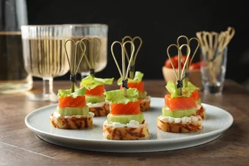 Tuinposter Tasty canapes with salmon, cucumber, bread and cream cheese on wooden table, closeup © New Africa