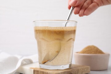 Dietary fiber. Woman stirring psyllium husk powder in water at table, closeup