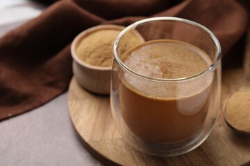 Soluble fiber with water in glass and powder on brown table, closeup