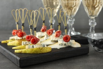 Tasty canapes with pears, blue cheese and prosciutto on grey table, closeup