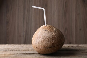 Coconut water. Fresh nut with straw on wooden table - obrazy, fototapety, plakaty