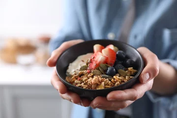 Fotobehang Woman holding bowl of tasty granola with berries, yogurt and seeds indoors, closeup © New Africa