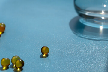 glass and yellow capsules on a blue background