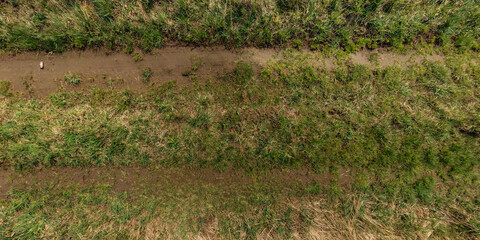 view from above on texture of gravel road among grass field - 783118290