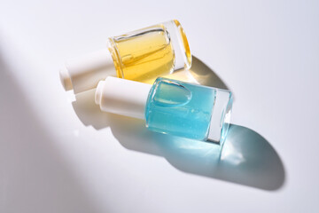 Yellow and blue serums with pipettes against the background of the sun.