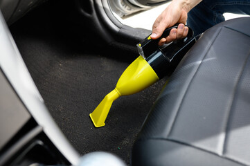  Cleaning upholstery of black carpets in car interior from dirt, dust and sand with a handheld...