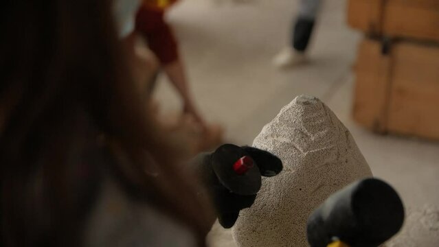Close-up of girl's hands making a stone sculpture using a chisel and hammer in a workshop.