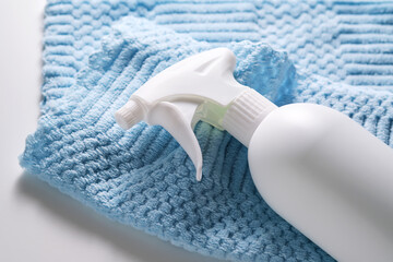 Cleaning product with a sprayer on a background of a blue microfiber cloth.