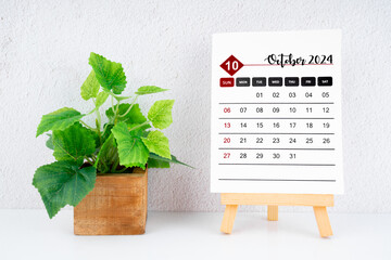 October 2024 calendar page and wooden plant pot.