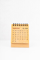 Brown mini desk calendar for September 2024 on white.