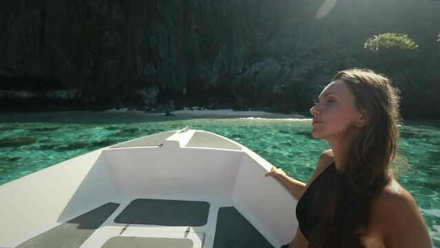 A woman is seated on a boat as it glides through the water, enjoying a serene boat tour in the beautiful El Nido Islands, Philippines.