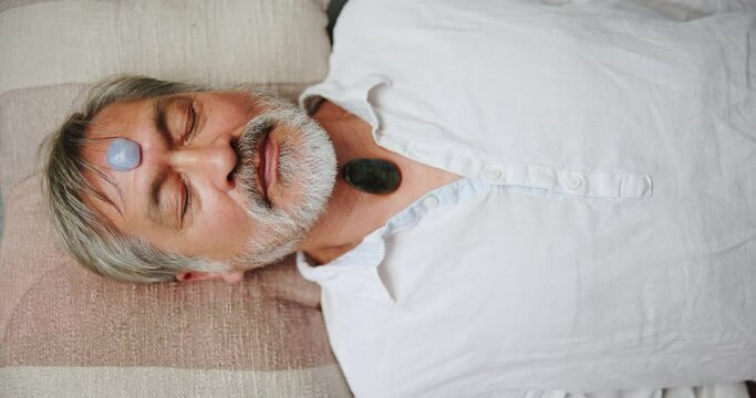 Holistic, healing and man with stone on body for indigenous chakra meditation and relax with peace from crystal. Spiritual, culture and person with rock from reiki healer to help wellness and detox