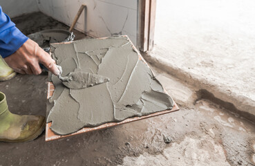 Hand tiler plastering cement glue with trowel on tile installing floor project, Real action worker in construction site