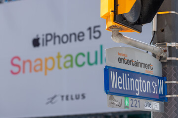Fototapeta premium city of Toronto street sign at Wellington Street West (with billboard featuring an Apple cell phone ad)