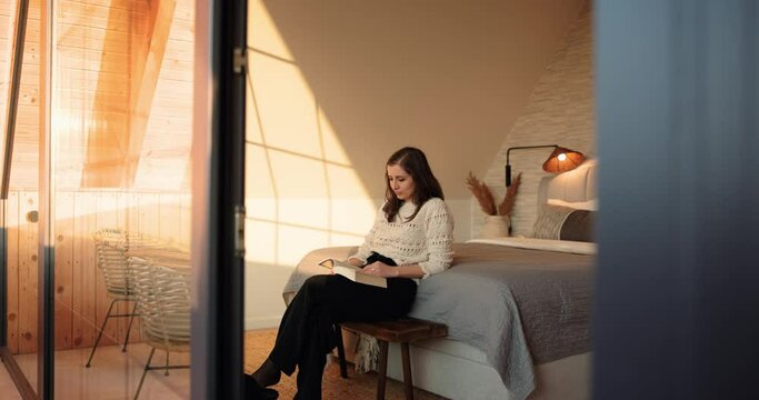 Golden Hour Reading, Young Woman with Book on Bench by Cozy Modern Bedroom, Leisure Concept