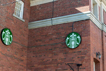 Fototapeta premium double Starbucks coffee circle logo sign of mermaid on a brick wall located at 941 College Street in Toronto, Canada