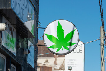Fototapeta premium round projecting sign on a blue sky of Sovereign Smoke, a cannabis store, located at 1220 Dupont Street in Toronto, Canada (west side)