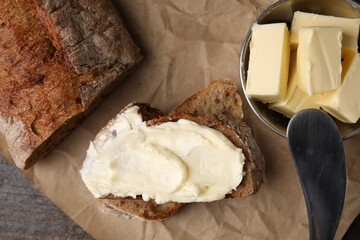 Tasty bread with butter and knife on table, flat lay
