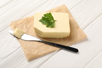 Tasty butter and knife on white wooden table