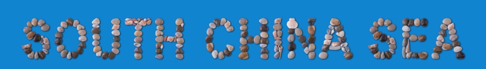 The geographical inscription “South China Sea” is lined with shells and stones of various shapes on a harmonious blue background. Water tourism, marine geology, study and ecology of the World Ocean