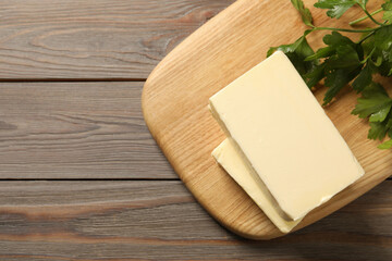 Tasty butter and parsley on wooden table, top view. Space for text