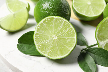 Fresh ripe limes and leaves on table, closeup