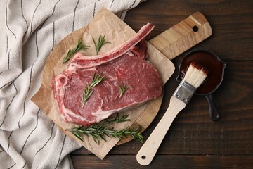 Raw meat, rosemary and marinade on wooden table, flat lay