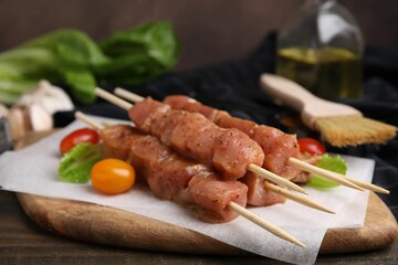 Skewers with cut raw marinated meat on wooden table, closeup