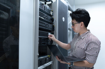 Computer engineer is setting up network in server room,Systems Maintenance Technician,Male engineer working in server room at modern data center
