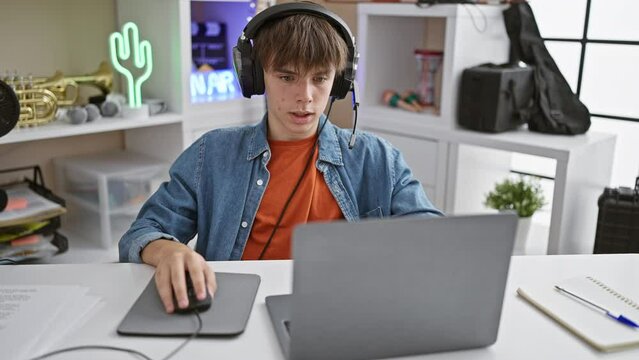 A young caucasian male teenager focused on working with his laptop in a modern home interior.