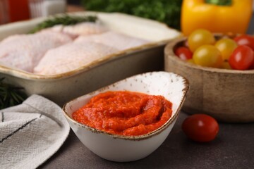 Fresh marinade, raw chicken and tomatoes on brown table, closeup