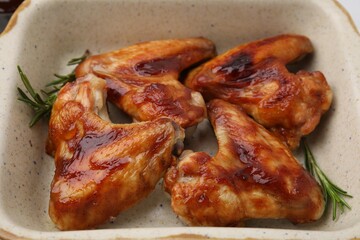 Fresh marinated chicken wings and rosemary in baking dish, closeup