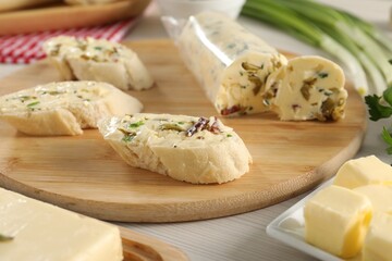 Tasty butter with olives, green onion and bread on wooden table, closeup