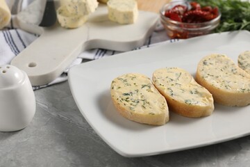 Tasty butter with dill and bread on grey marble table, closeup