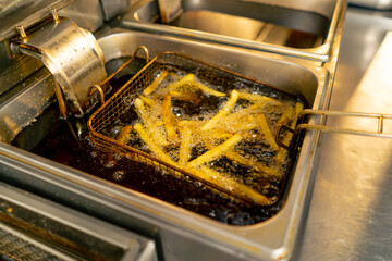 close-up in professional kitchen frying French fries in oil in a deep fryer