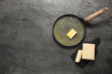 Melting butter in frying pan and dairy product on grey table, top view. Space for text