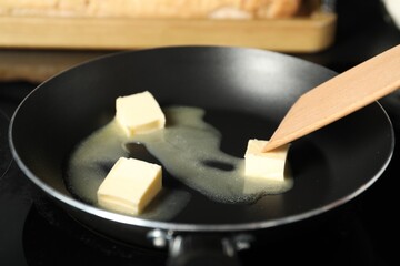 Stirring melting butter in frying pan on table, closeup