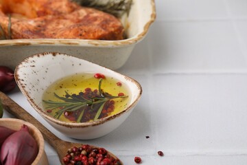 Fresh marinade and cooked fish on white tiled table, closeup. Space for text