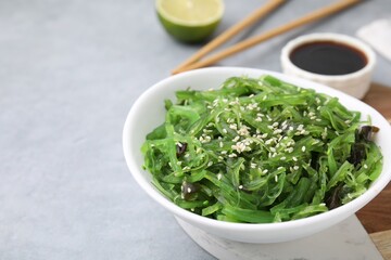 Tasty seaweed salad in bowl served on gray table, closeup. Space for text