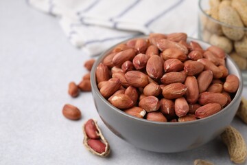 Fresh unpeeled peanuts in bowl on grey table, closeup. Space for text