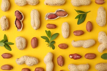 Fresh peanuts and leaves on yellow table, flat lay