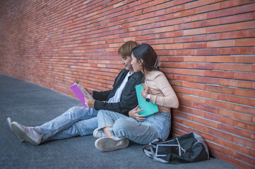 Male and female students sit and review their textbooks on the sidewalk on campus. Before the end of the semester