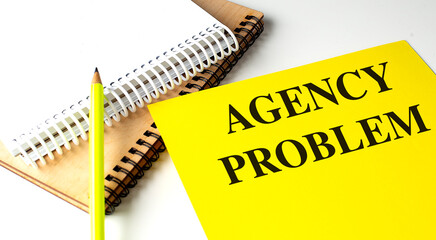 AGENCY PROBLEM text on yellow paper with notebooks