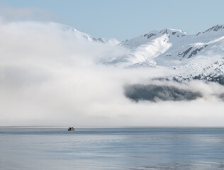 Boat approaching fog on the mountains and sea in Passage Canal, Whittier, Alaska USA