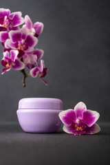 Lilac cosmetic cream jar, product mockup on dark background with orchid flower