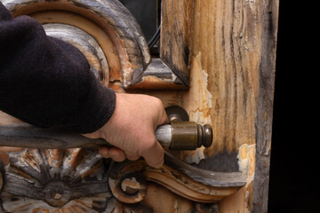 Hand opens a wooden door.
