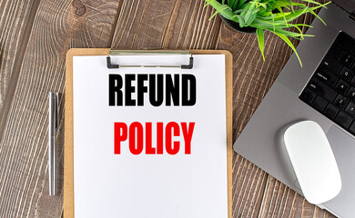 REFUND POLICY text on clipboard paper with laptop, mouse and pen