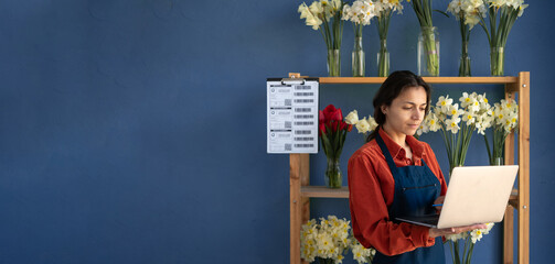 Hispanic woman florist using laptop in flower Store. Female worker working, small business owner....