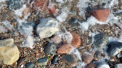 rund gewaschene Steine am Ostseestrand im Wasser mit Wellen
